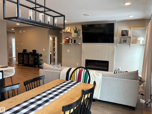 Open concept living area featuring recessed lighting, a modern linear chandelier, and light wood flooring - 137 Graybriar Drive, Stony Plain, AB - Indoor Photo Showing Dining Room With Fireplace
