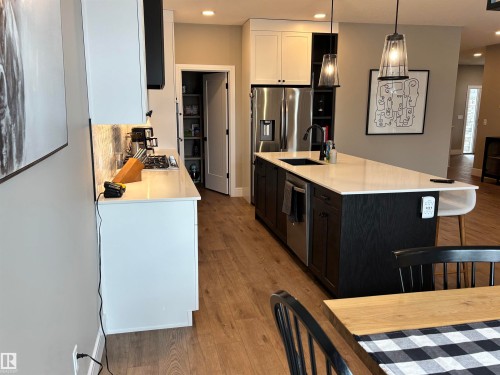 This kitchen features an expansive island with a contrasting dark wood base and a light-colored countertop, complemented by pendant lighting - 137 Graybriar Drive, Stony Plain, AB - Indoor Photo Showing Kitchen With Upgraded Kitchen