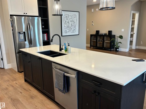 The kitchen features a large island with a white countertop and a black sink - 137 Graybriar Drive, Stony Plain, AB - Indoor Photo Showing Kitchen With Stainless Steel Kitchen With Double Sink With Upgraded Kitchen