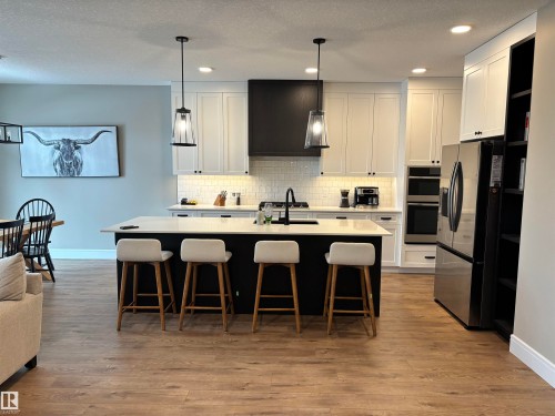 The kitchen features a central island with seating for four, white shaker-style cabinetry, and stainless steel appliances - 137 Graybriar Drive, Stony Plain, AB - Indoor Photo Showing Kitchen With Stainless Steel Kitchen With Upgraded Kitchen