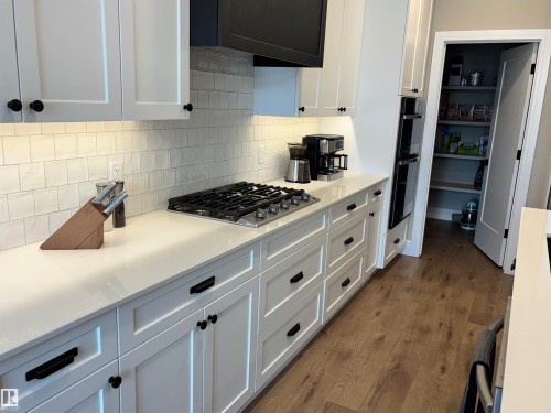 The kitchen features white cabinetry with dark hardware, light countertops, and a white subway tile backsplash - 137 Graybriar Drive, Stony Plain, AB - Indoor Photo Showing Kitchen With Upgraded Kitchen