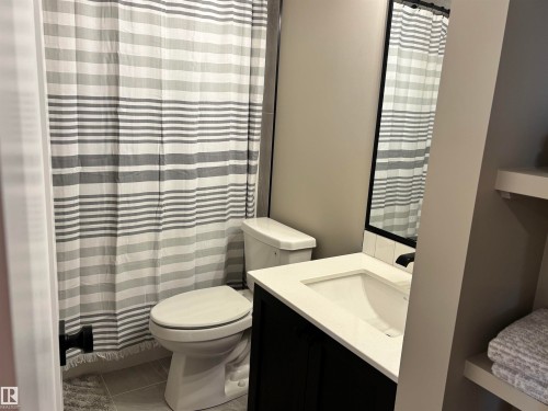 Bathroom featuring a vanity with a white countertop and a rectangular sink, a toilet, and a shower with a striped curtain - 137 Graybriar Drive, Stony Plain, AB - Indoor Photo Showing Bathroom
