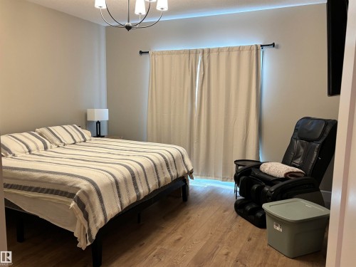 Bedroom featuring light-colored walls, wood-look flooring, and a contemporary chandelier - 137 Graybriar Drive, Stony Plain, AB - Indoor Photo Showing Bedroom