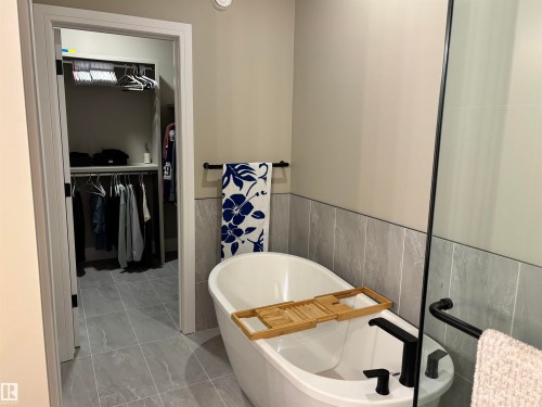 Bathroom featuring a freestanding white bathtub with a black faucet, glass shower enclosure, and tiled walls - 137 Graybriar Drive, Stony Plain, AB - Indoor Photo Showing Bathroom