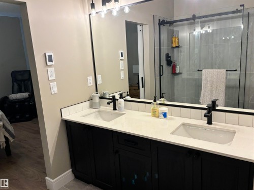 Bathroom featuring a double vanity with dark cabinetry, light-colored countertops, and matte black fixtures - 137 Graybriar Drive, Stony Plain, AB - Indoor Photo Showing Bathroom