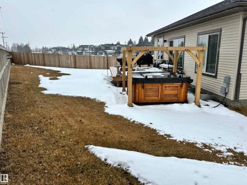The property features a private yard with a wooden fence, a hot tub with a wooden surround, and a light-colored siding exterior - 137 Graybriar Drive, Stony Plain, AB - Outdoor