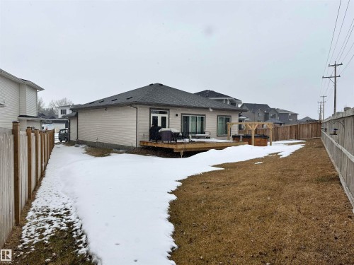 The property features a spacious rear yard with a wooden fence, a deck with exterior doors, and a pergola - 137 Graybriar Drive, Stony Plain, AB - Outdoor