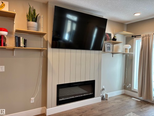 Living area featuring a modern electric fireplace with a panel accent wall, recessed lighting, and hardwood flooring - 137 Graybriar Drive, Stony Plain, AB - Indoor With Fireplace