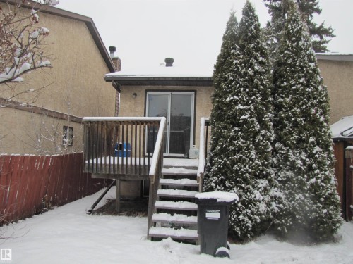 The property features a wooden deck with railing and stairs, leading to a sliding glass door - 3617 43A Avenue, Edmonton, AB - Outdoor