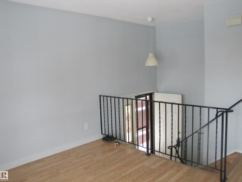 Open space featuring light-toned flooring, a black metal railing, and a white pendant light fixture - 3617 43A Avenue, Edmonton, AB - Indoor Photo Showing Other Room