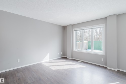 Spacious room featuring light gray walls, dark wood flooring, and a large window providing natural light - 14007 164 Avenue, Edmonton, AB - Indoor Photo Showing Other Room