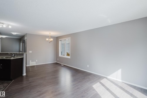 This bright living space features hardwood flooring and a window with horizontal blinds, providing natural light - 14007 164 Avenue, Edmonton, AB - Indoor