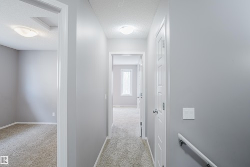 Well-lit hallway with neutral gray walls and light-colored carpet, providing access to other areas of the property - 14007 164 Avenue, Edmonton, AB - Indoor Photo Showing Other Room