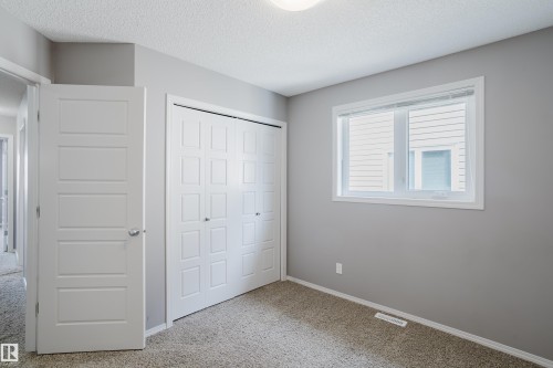 This room features a window providing natural light, a closet with bi-fold doors, and neutral grey walls - 14007 164 Avenue, Edmonton, AB - Indoor