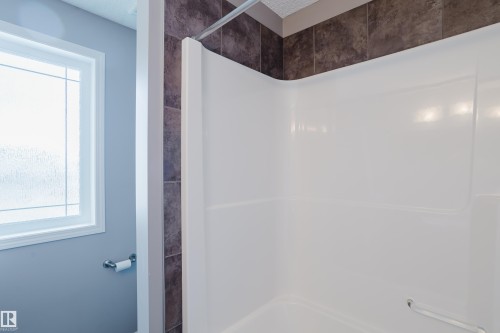 Bathroom with a white shower/tub combination featuring a curved shower rod and dark tiled surround - 14007 164 Avenue, Edmonton, AB - Indoor Photo Showing Bathroom