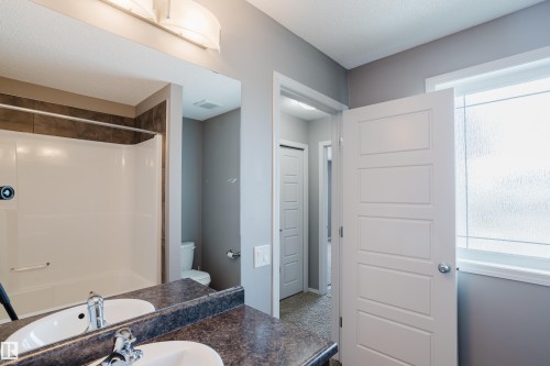 Bathroom featuring a double vanity with two sinks, a window with privacy glass, and a shower-tub combination with tiled surround - 14007 164 Avenue, Edmonton, AB - Indoor Photo Showing Bathroom