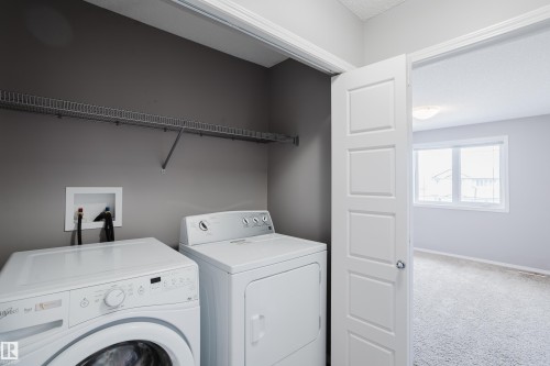 Dedicated laundry area featuring a washer and dryer, a wall-mounted shelf, and a light gray wall color - 14007 164 Avenue, Edmonton, AB - Indoor Photo Showing Laundry Room