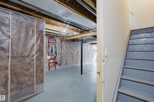 Unfinished basement space with exposed wooden beams, painted concrete floors, and a visible electrical panel - 14007 164 Avenue, Edmonton, AB - Indoor Photo Showing Basement