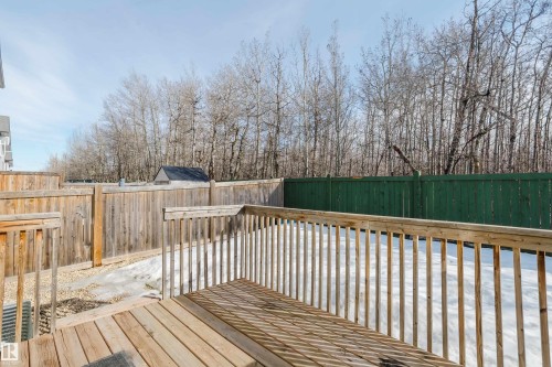 The property features a wooden deck with railings, offering views of the surrounding natural landscape with mature trees - 14007 164 Avenue, Edmonton, AB - Outdoor