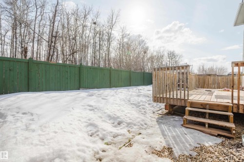 The property features a wooden deck with railing and stairs, a green wooden fence, and a partially snow-covered yard - 14007 164 Avenue, Edmonton, AB - Outdoor