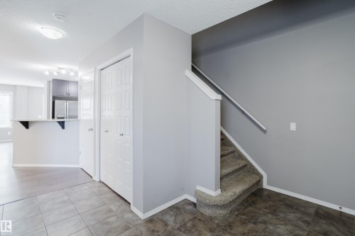 View from the front entryway with tiled flooring, leading to a carpeted staircase with a white handrail - 14007 164 Avenue, Edmonton, AB - Indoor Photo Showing Other Room