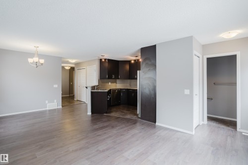 This open-concept interior features wood-style flooring, light grey painted walls, and a modern kitchen with dark cabinetry and countertops - 14009 164 Avenue, Edmonton, AB - Indoor Photo Showing Kitchen