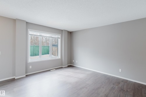 The room features a large window, light gray walls, dark wood-style flooring, and white trim - 14009 164 Avenue, Edmonton, AB - Indoor Photo Showing Other Room