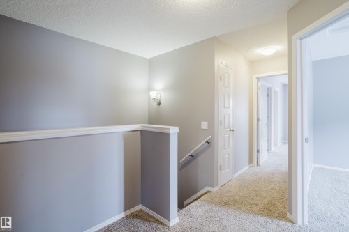 Bright hallway featuring light-colored carpet, white doors, and a wall-mounted light fixture - 14009 164 Avenue, Edmonton, AB - Indoor Photo Showing Other Room