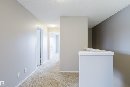 The property features light-colored carpeting, neutral-toned walls, and white trim throughout the hallway - 14009 164 Avenue, Edmonton, AB - Indoor Photo Showing Other Room