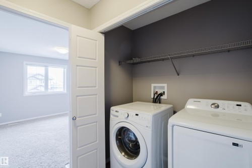 Dedicated laundry area featuring a washer and dryer, a built-in wire shelf, and a painted accent wall - 14009 164 Avenue, Edmonton, AB - Indoor Photo Showing Laundry Room