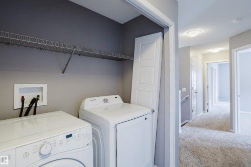 The property features a dedicated laundry area with a washer and dryer, a wire shelf, and a light gray wall - 14009 164 Avenue, Edmonton, AB - Indoor Photo Showing Laundry Room