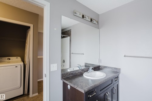 Bathroom featuring a dark wood vanity with a white basin and a large mirror - 14009 164 Avenue, Edmonton, AB - Indoor Photo Showing Laundry Room