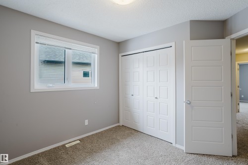 This room features a window with blinds, carpeted flooring, and a bi-fold closet with panel doors - 14009 164 Avenue, Edmonton, AB - Indoor