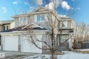 The property features a two-story exterior with light gray siding and stone accents, a dark shingle roof, and white-paneled garage doors - 14009 164 Avenue, Edmonton, AB  - Outdoor 