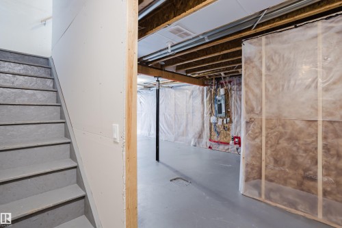 The property features an unfinished lower level with exposed ceiling joists, a staircase with painted treads, and a concrete floor - 14009 164 Avenue, Edmonton, AB - Indoor Photo Showing Basement
