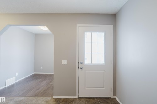 Entryway featuring light neutral wall paint, a white door with a window grid, and a view into an adjoining room with wood-style flooring - 14009 164 Avenue, Edmonton, AB - Indoor Photo Showing Other Room