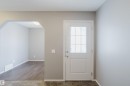 Entryway featuring light neutral wall paint, a white door with a window grid, and a view into an adjoining room with wood-style flooring - 14009 164 Avenue, Edmonton, AB  - Indoor Photo Showing Other Room 