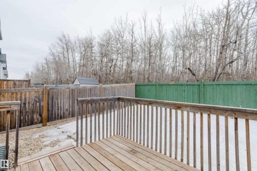 The property features a wooden deck, a wooden fence, and a yard with snow and gravel - 14009 164 Avenue, Edmonton, AB - Outdoor With Exterior