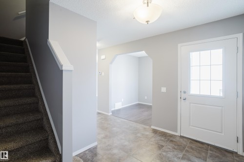 The entrance foyer features tile flooring, a white front door with a window, and a staircase with carpeted treads - 14009 164 Avenue, Edmonton, AB - Indoor Photo Showing Other Room