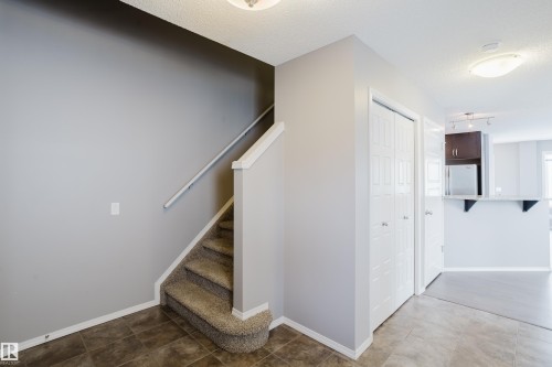 The entryway features tile flooring, a carpeted stairway with a white handrail, and white bi-fold closet doors - 14009 164 Avenue, Edmonton, AB - Indoor Photo Showing Other Room