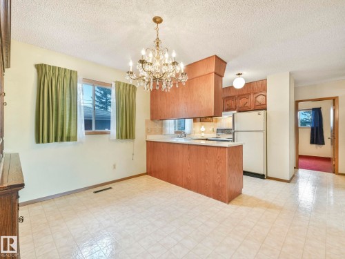Kitchen and dining area featuring tiled flooring, a chandelier, and wood cabinetry - 5904 84 Avenue, Edmonton, AB - Indoor Photo Showing Kitchen