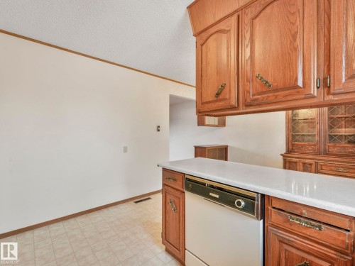The kitchen features wood cabinetry, a white countertop, and a white dishwasher - 5904 84 Avenue, Edmonton, AB - Indoor Photo Showing Kitchen