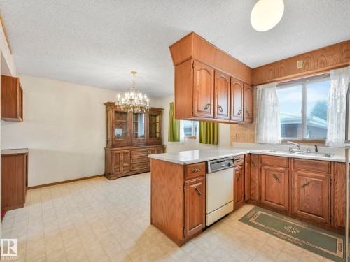 The property features a kitchen with wood cabinetry, a white countertop, and a window above the sink - 5904 84 Avenue, Edmonton, AB - Indoor Photo Showing Kitchen