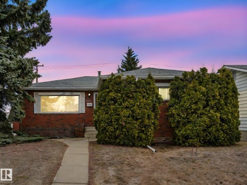 The property features a brick exterior with white trim and a prominent front window with white shutters - 5904 84 Avenue, Edmonton, AB - Outdoor