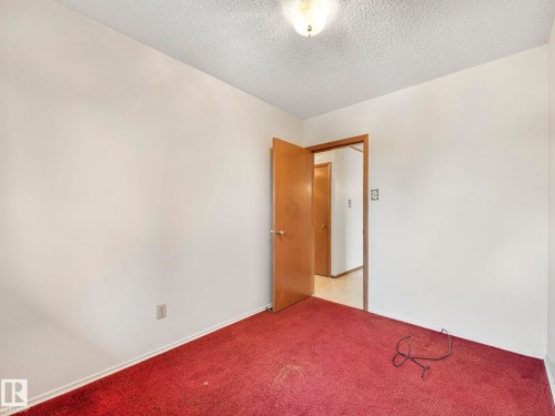 This room features a neutral wall color, overhead lighting, and a red carpet - 5904 84 Avenue, Edmonton, AB - Indoor Photo Showing Other Room