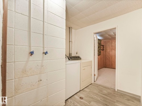 Laundry area with a washer and dryer, featuring light wood-look flooring and a drop ceiling - 5904 84 Avenue, Edmonton, AB - Indoor