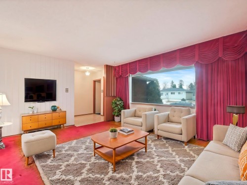 The property features a spacious living area with large windows, red carpeting, and a decorative valance - 5904 84 Avenue, Edmonton, AB - Indoor Photo Showing Living Room