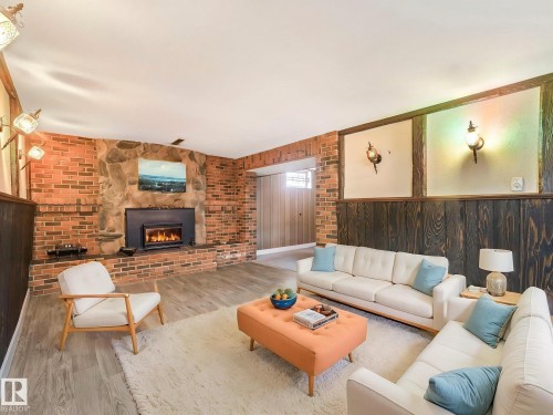 Living room featuring a brick and stone fireplace with a wood-burning insert, wood paneling, and light wood flooring - 5904 84 Avenue, Edmonton, AB - Indoor Photo Showing Living Room With Fireplace