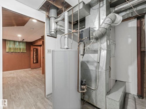 This area features a water heater and ductwork, with light-colored flooring extending into an adjacent space - 5904 84 Avenue, Edmonton, AB - Indoor Photo Showing Basement