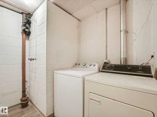Laundry area featuring a washer and dryer, concrete block walls, and a drop ceiling - 5904 84 Avenue, Edmonton, AB - Indoor Photo Showing Laundry Room